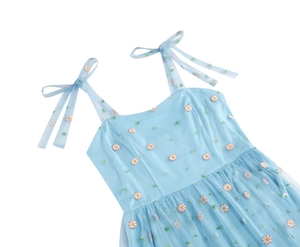 Detail of light blue mesh dress featuring daisy embroidery and bow-tie shoulder straps