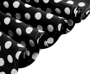 Dettaglio del tessuto a pois bianchi su nero con pieghe eleganti e cuciture di qualità