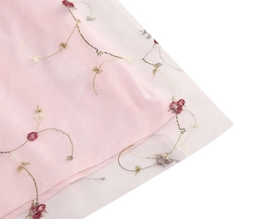 Detailansicht eines rosa Netzmieders mit Goldstickerei und roten Blumenakzenten