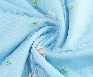 Close-up of intricate floral embroidery on light blue mesh fabric with delicate textures