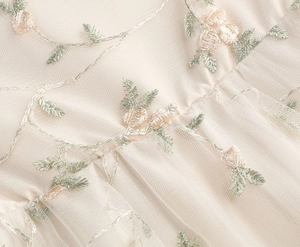Gros plan sur la broderie florale élégante sur tulle beige pour robe de princesse