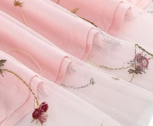 Detailaufnahme von rosa Tüllschichten mit feiner dunkelroter Blumenstickerei auf dem Stoff