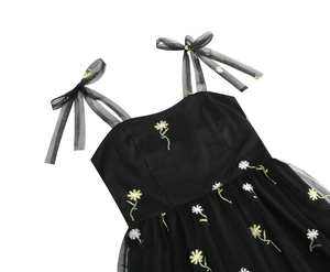 Detailed view of yellow daisy embroidery on black sheer mesh dress with bow straps
