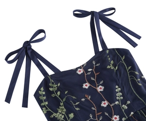 Detail of navy blue dress with floral embroidery and adjustable bow shoulder strap