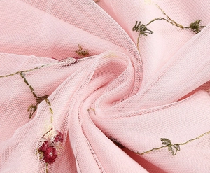 Nahaufnahme von rosa Tüllstoff mit feiner Blumenstickerei und Rankenmustern