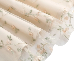 Détail du tissu en tulle beige avec broderies de roses 3D colorées et motifs floraux