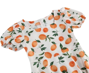Close-up of girls square neck white dress with orange citrus print and puff sleeves