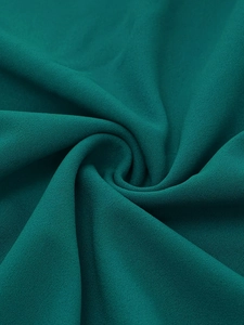 Detailed macro view showing the deep teal crepe fabric texture and elegant pleated ripples