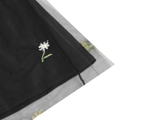 Close-up of intricate daisy embroidery on black mesh tulle dress with inner lining