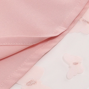 Detail of pink butterfly embroidery on mesh fabric for a summer backless dress