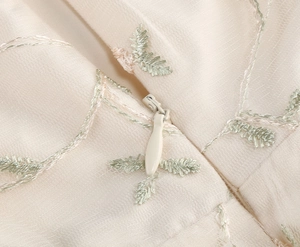 Vue macro de la fermeture éclair invisible et broderie florale sur robe de fille en tulle