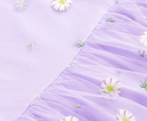 Detail of purple tulle dress showing exquisite daisy floral embroidery and layered pleats