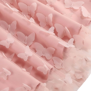 Macro detail of pink mesh dress featuring 3D butterfly appliques and silver stitching
