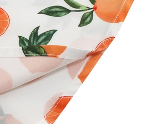 Detail shot of white woven fabric with orange prints and neat hem stitching