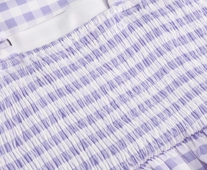 Close-up of pink gingham fabric showing detailed smocking and elastic pleated texture