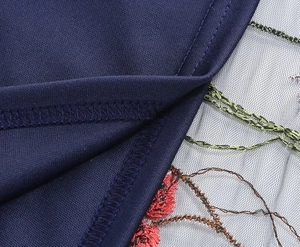 Macro shot of navy knit fabric with detailed floral embroidery on sheer mesh panel