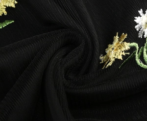 Close-up of intricate floral embroidery on black tulle fabric showing textured mesh detail