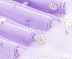 Close-up of lavender mesh fabric with delicate daisy embroidery and soft lace texture