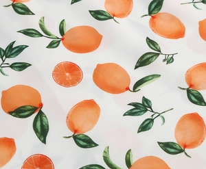 Close-up of summer girls dress fabric featuring fresh lemon and citrus fruit prints
