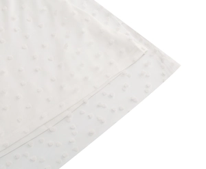 Close-up of white mesh fabric with delicate heart-shaped polka dots and layered hem details