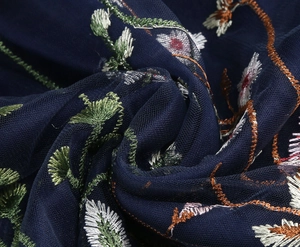 Detailed macro view of the intricate floral embroidery on navy blue mesh fabric