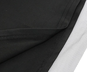 Detailed view of black dress hem with white mesh overlay and precise overlock stitching