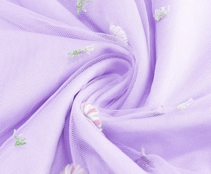 Macro shot of purple mesh fabric featuring intricate floral embroidery and leaf details