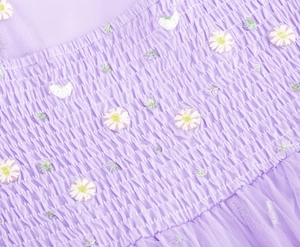 Detail of lavender smocked bodice with delicate daisy floral embroidery and mesh pleats