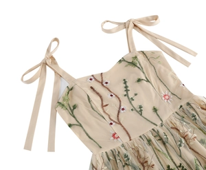 Close-up of floral embroidery on beige tulle dress with elegant bow strap details