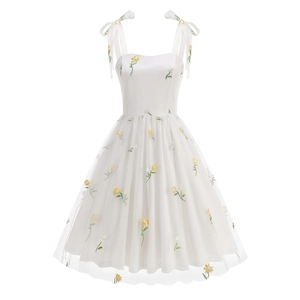 Detail of delicate yellow floral embroidery on white tulle dress with adjustable tie straps