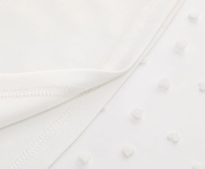 Detail of white mesh skirt featuring flocked heart patterns and fine edge stitching