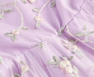 Broderie détaillée de feuilles argentées et fleurs roses sur tissu tulle en maille mauve