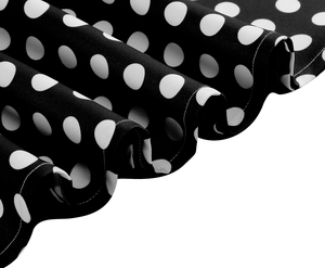 Détail macro du tissu à pois noirs avec coutures blanches précises sur l'ourlet de robe