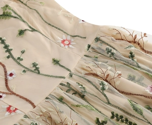 Close-up of champagne mesh dress featuring intricate floral embroidery and pleated waist