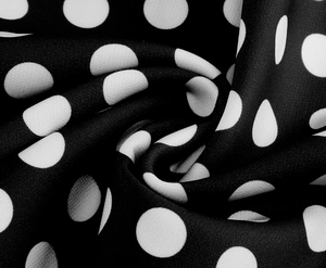 Vue détaillée du tissu noir à pois blancs montrant la texture douce et le beau drapé