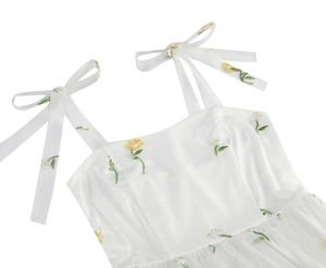 Detail view of yellow floral embroidery on white tulle dress with bow shoulder straps