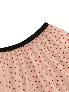 Close-up of pink tulle skirt featuring red heart patterns and a black elastic waistband