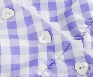 Detail of purple gingham dress featuring scalloped edges and white heart-shaped buttons