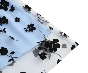 Detail of light blue dress showing white mesh overlay with elegant black floral embroidery