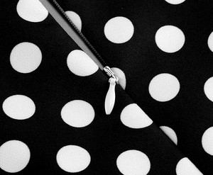 Gros plan sur la fermeture éclair invisible et le tissu à pois de la robe rétro