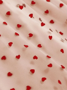 Detailed macro view of pink tulle fabric featuring 3D red heart flocked patterns