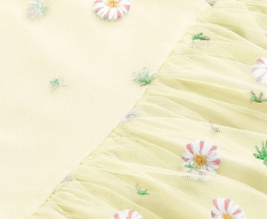 Close-up of embroidered mesh fabric with yellow floral daisy patterns on a dress