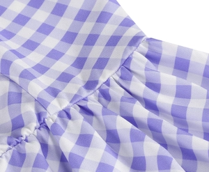 Close-up of purple gingham dress fabric with pleated waist details and woven texture