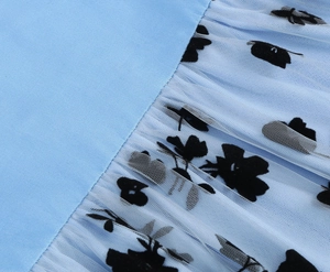 Detail of light blue mesh fabric with black floral flocking and pleated texture design