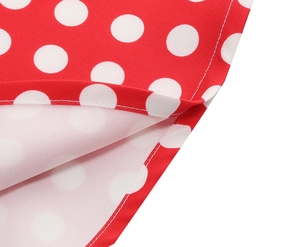 Détail du tissu rouge à pois blancs montrant la couture propre de l'ourlet et la texture