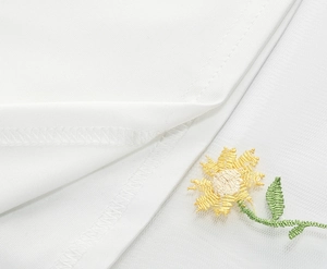Detail of sunflower embroidery on white tulle fabric with delicate mesh stitching