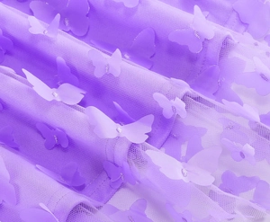 Dettaglio di tessuto in tulle viola con farfalle 3D applicate su gonna in mesh