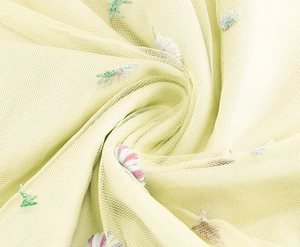 Macro shot of embroidered floral mesh fabric with delicate pink flowers and green leaves