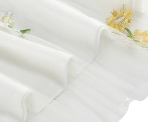 Close-up of intricate sunflower and small floral embroidery on white tulle mesh fabric