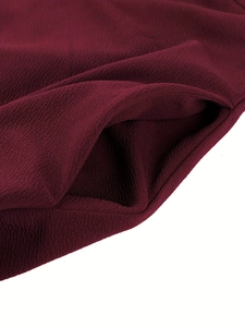 Detailed close-up of side pocket on dark red evening gown with textured crepe fabric